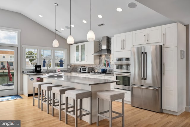 kitchen with appliances with stainless steel finishes, wall chimney exhaust hood, decorative backsplash, white cabinets, and recessed lighting