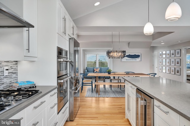 kitchen featuring range hood, stainless steel gas cooktop, wine cooler, dark countertops, and light wood-style floors