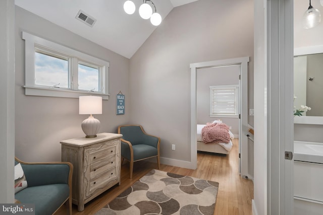 sitting room with light wood finished floors, baseboards, and high vaulted ceiling