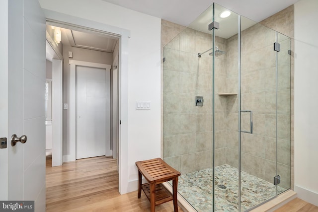 full bathroom with a shower stall, wood finished floors, and baseboards