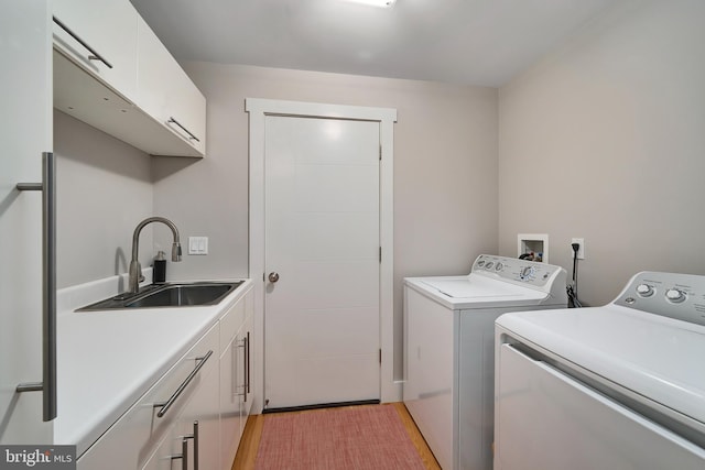 laundry area featuring cabinet space, washing machine and dryer, and light wood-type flooring