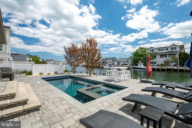 view of swimming pool featuring a patio area, area for grilling, fence, and a water view