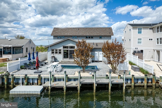 back of property with a fenced backyard, a water view, a patio, and a sunroom