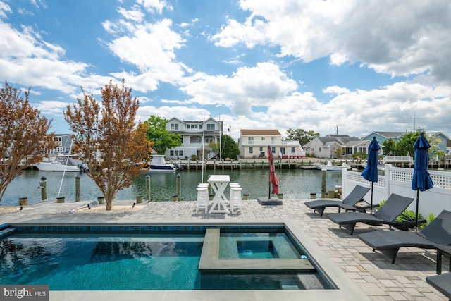 outdoor pool with an in-ground hot tub, a patio area, a water view, and a residential view