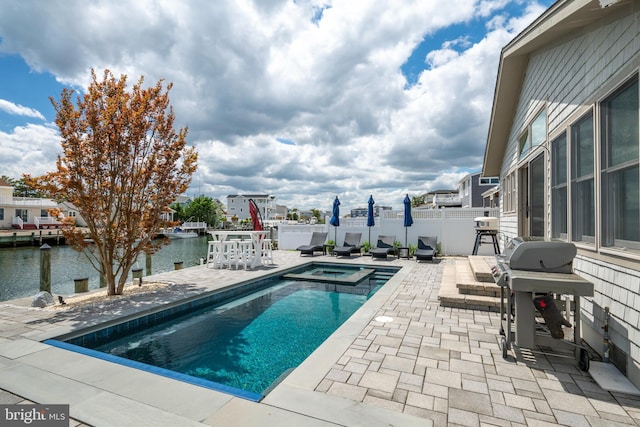 view of pool with a patio area, a water view, fence, and a pool with connected hot tub