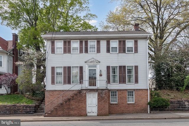 colonial house with a chimney and brick siding