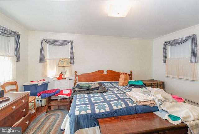 bedroom with wood finished floors and ornamental molding