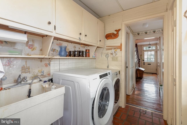 laundry area with a sink, cabinet space, brick floor, and independent washer and dryer