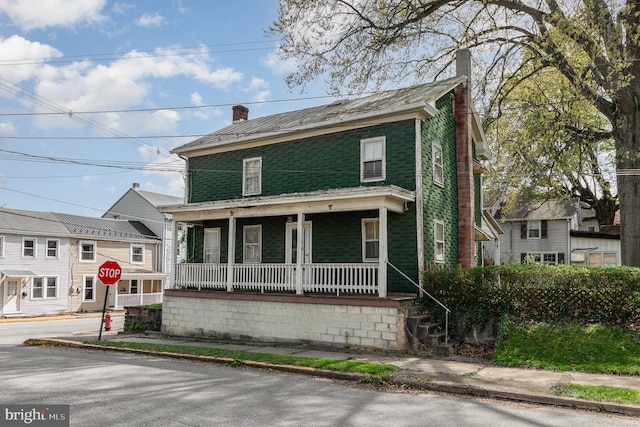 view of front facade with a chimney and covered porch