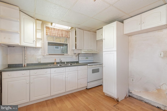 kitchen with a paneled ceiling, a sink, under cabinet range hood, white electric stove, and dark countertops