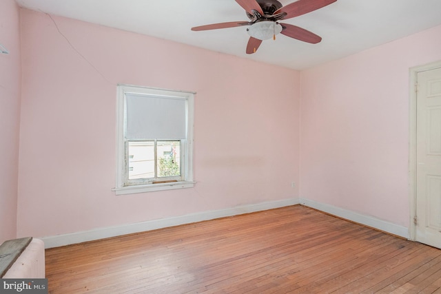 empty room with ceiling fan, light wood-type flooring, and baseboards