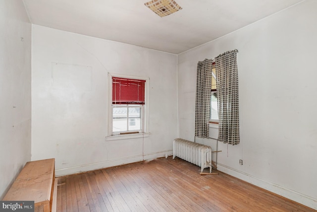 unfurnished room with hardwood / wood-style floors, radiator heating unit, and baseboards