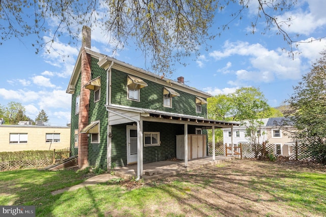 back of house featuring a lawn, fence, and a chimney