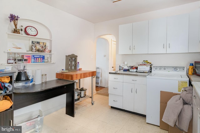 kitchen with white cabinets, light countertops, arched walkways, light floors, and washer / dryer