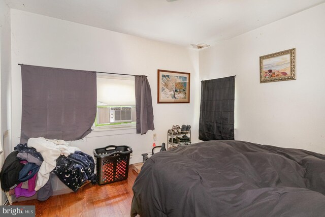 bedroom featuring wood finished floors and cooling unit