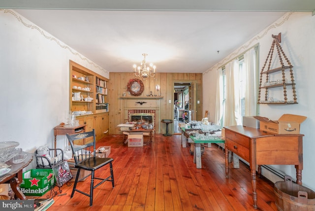 interior space featuring wood-type flooring, a notable chandelier, wood walls, and a fireplace