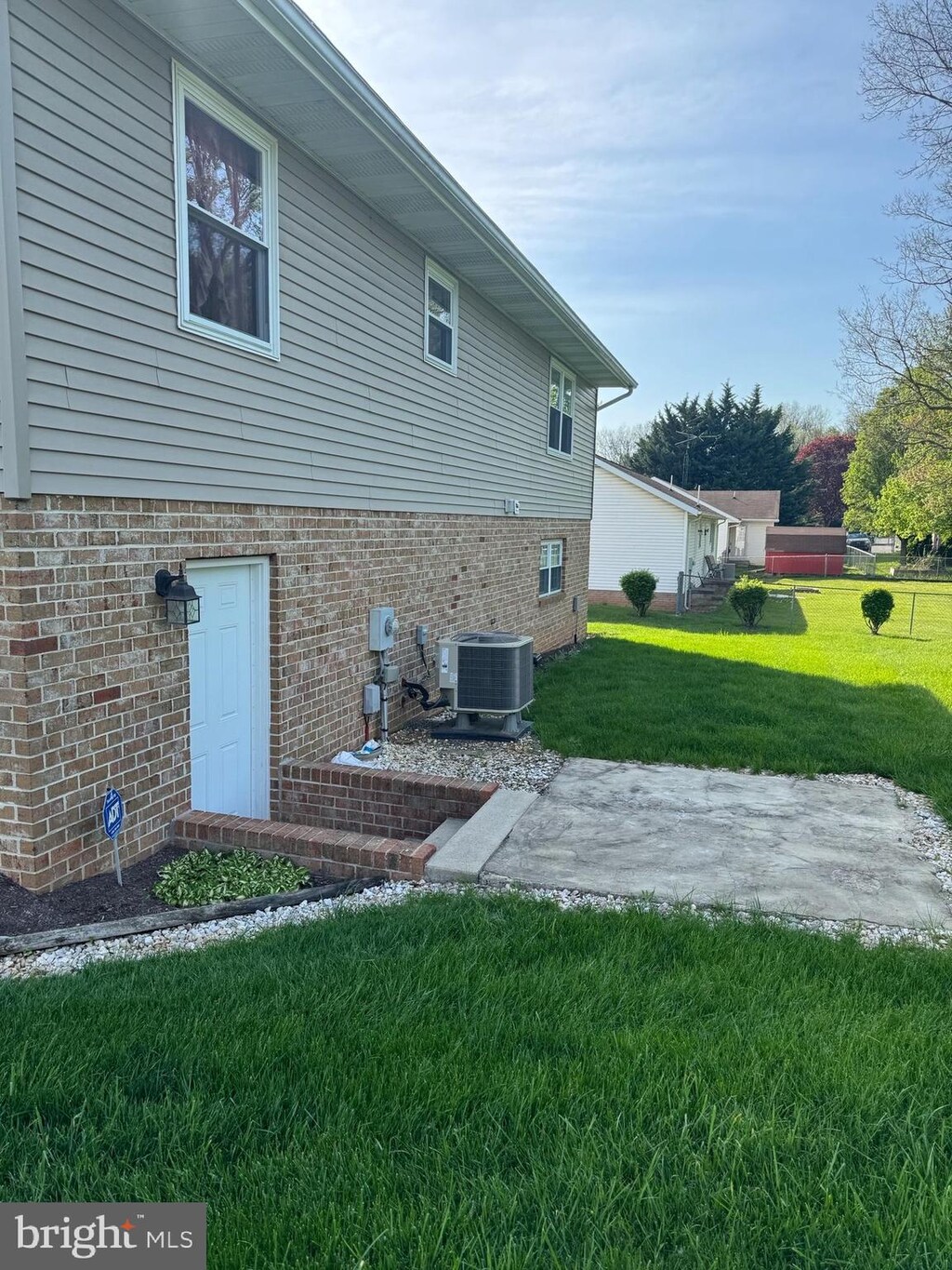 view of home's exterior with a lawn, brick siding, a patio area, and central air condition unit