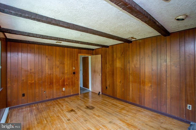 2500 Eberhart Rd, Quakertown, PA 18951 - empty room featuring wood walls, a textured ceiling, beam ceiling, and hardwood / wood-style floors