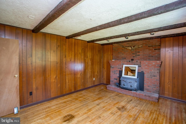 2500 Eberhart Rd, Quakertown, PA 18951 - unfurnished living room with wood-type flooring, wood walls, a wood stove, beam ceiling, and a textured ceiling