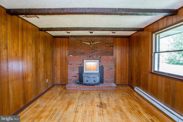 2500 Eberhart Rd, Quakertown, PA 18951 - unfurnished living room featuring beam ceiling, a wood stove, light wood-style floors, wood walls, and a baseboard radiator