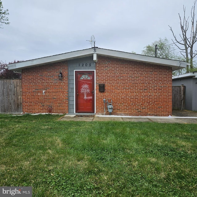 back of house featuring a yard, brick siding, and fence