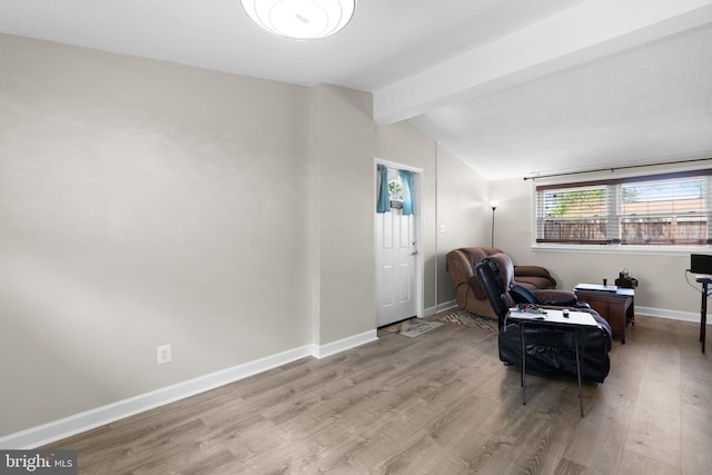 living area featuring baseboards, vaulted ceiling with beams, and wood finished floors