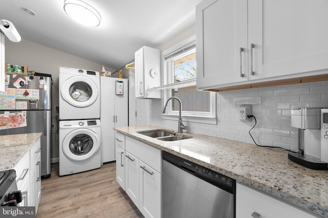 interior space featuring appliances with stainless steel finishes, tasteful backsplash, vaulted ceiling, a sink, and stacked washing maching and dryer