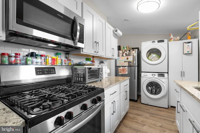 kitchen featuring white cabinetry, appliances with stainless steel finishes, stacked washer / dryer, and a toaster