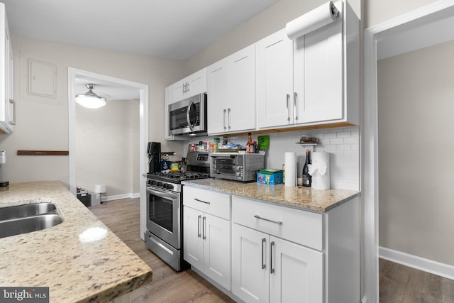 kitchen featuring white cabinetry, appliances with stainless steel finishes, wood finished floors, and a toaster