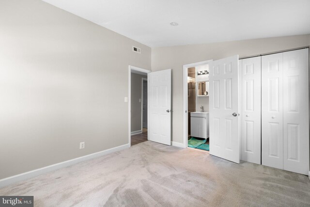 unfurnished bedroom with visible vents, vaulted ceiling, baseboards, a closet, and carpet flooring