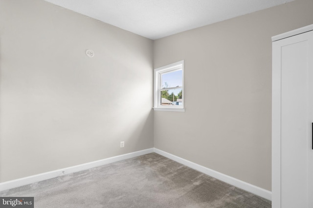 spare room with baseboards and carpet flooring