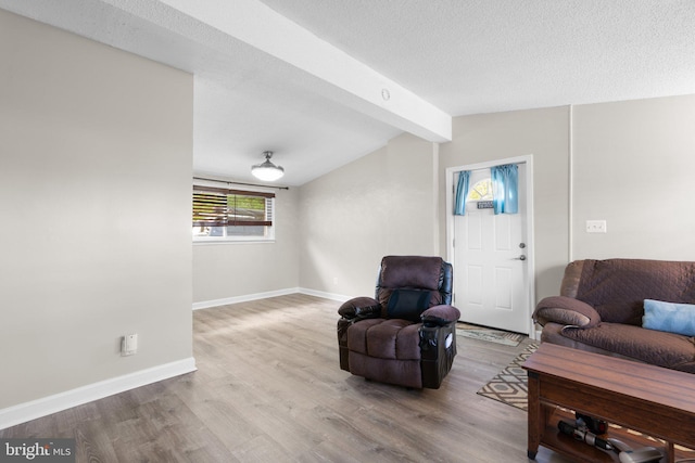 living room with vaulted ceiling with beams, baseboards, wood finished floors, and a textured ceiling