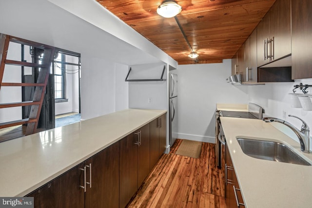 kitchen featuring wood finished floors, baseboards, light countertops, wood ceiling, and a sink