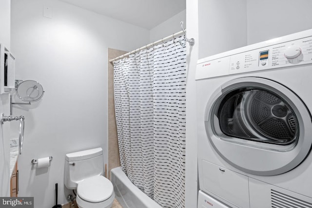 bathroom with washer / dryer, shower / bath combination with curtain, and toilet