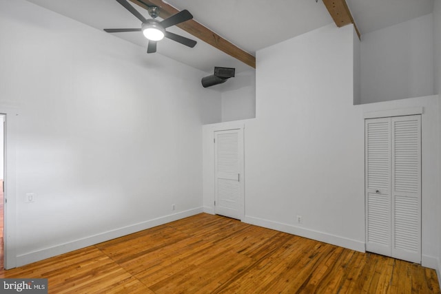 interior space with baseboards, beamed ceiling, high vaulted ceiling, and wood finished floors