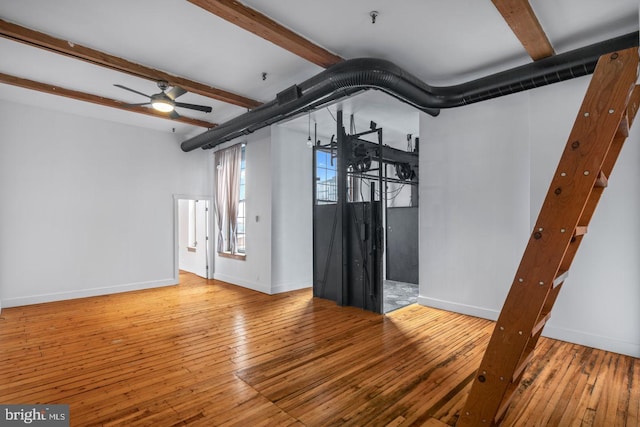 unfurnished living room featuring baseboards, ceiling fan, beamed ceiling, and wood-type flooring