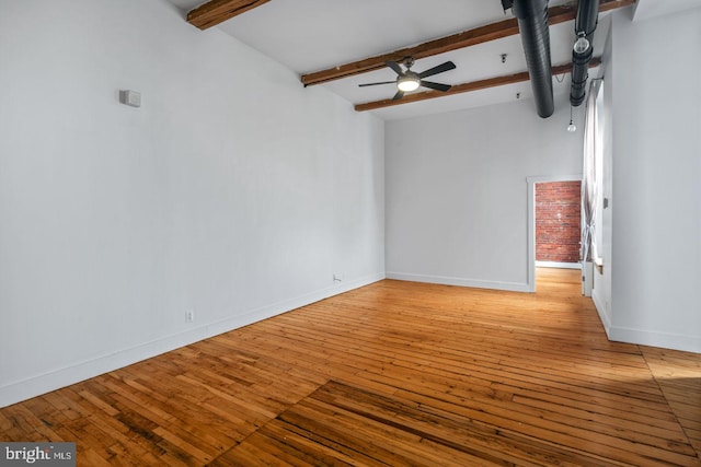 empty room with baseboards, a ceiling fan, light wood-type flooring, and beam ceiling