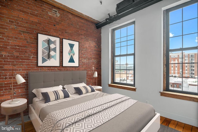 bedroom featuring brick wall, baseboards, and wood finished floors