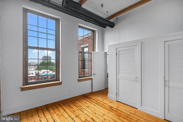 unfurnished bedroom featuring baseboards, two closets, and light wood-style flooring