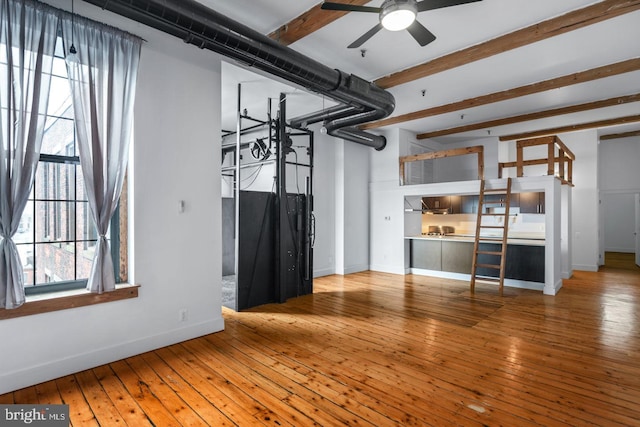 unfurnished living room with baseboards, ceiling fan, beam ceiling, and hardwood / wood-style flooring