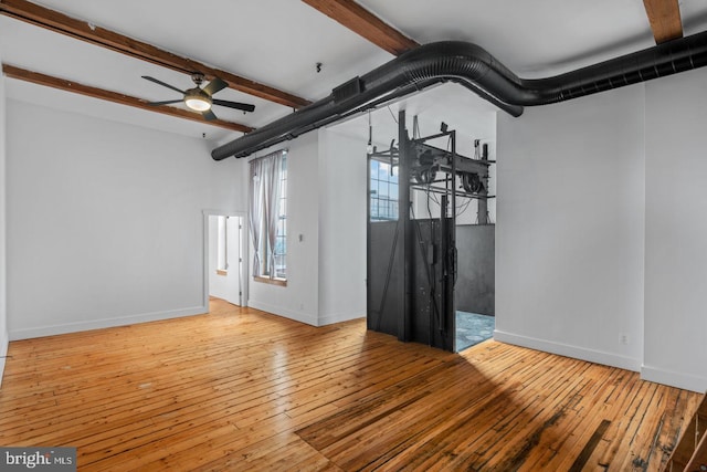 spare room featuring wood-type flooring, a ceiling fan, baseboards, and beamed ceiling
