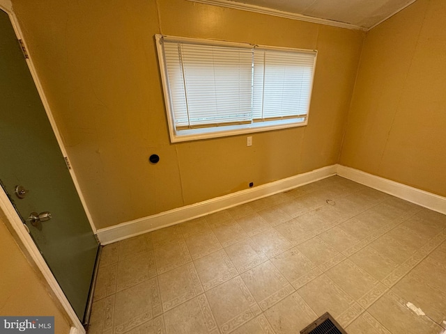 empty room featuring ornamental molding and baseboards