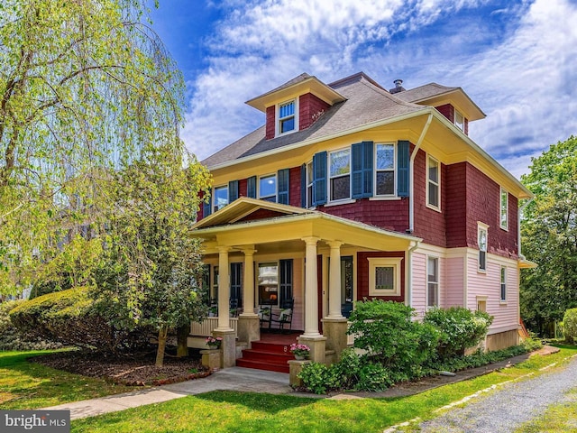 american foursquare style home with covered porch and a shingled roof