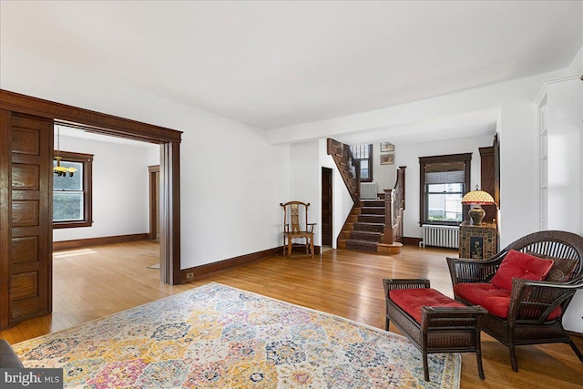 sitting room featuring baseboards, stairway, wood finished floors, and radiator
