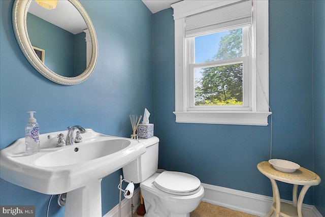bathroom with a healthy amount of sunlight, baseboards, toilet, and a sink