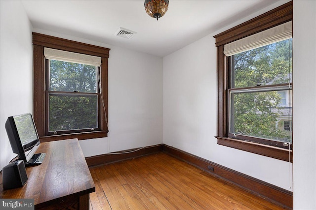 unfurnished office with baseboards, visible vents, and wood finished floors