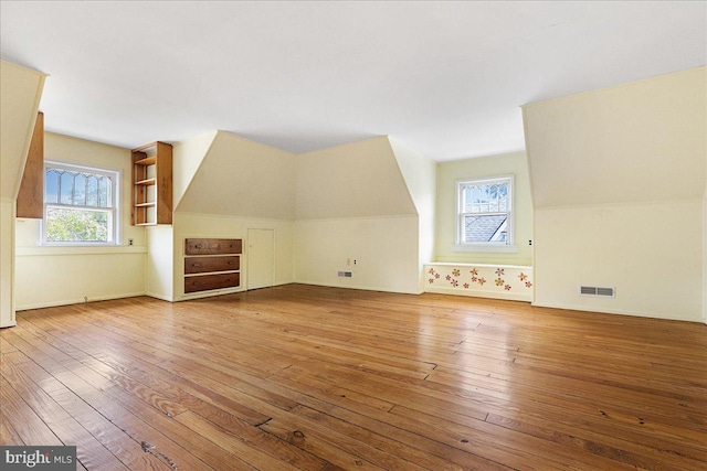 bonus room with baseboards, visible vents, and hardwood / wood-style floors
