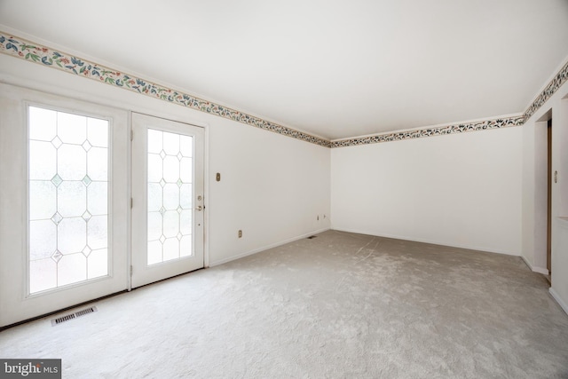 spare room featuring light carpet and baseboards