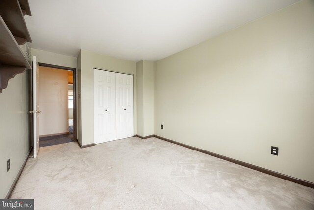 unfurnished bedroom with light colored carpet, baseboards, and a closet