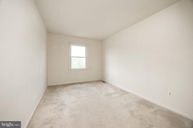 spare room with light carpet and baseboards